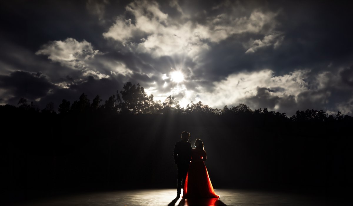 Pre-wedding couple shoot by WeddingClickz — silhouette against a breaking sky